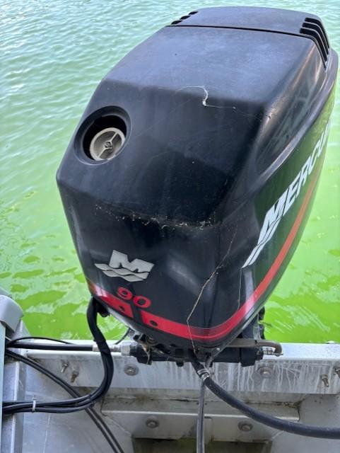 Outboard motor on a boat, Monarch 240, 2001 model, against green water background.