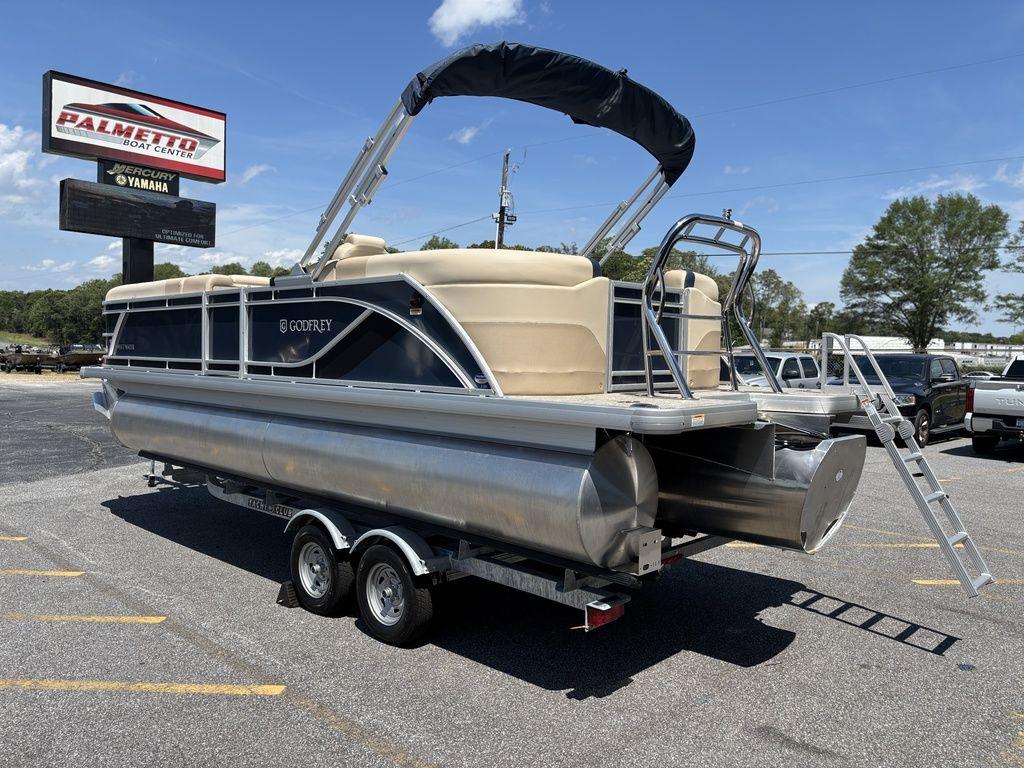 2025 Godfrey SWEETWATER 2286 SB pontoon boat on trailer in parking lot.