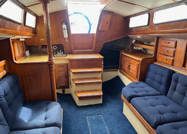 Interior of 1978 Islander Sloop 36 sailboat with wooden cabinetry and blue seating.