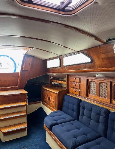 Interior of a 1978 Islander Sloop 36 sailboat with wooden cabinetry and blue seating.