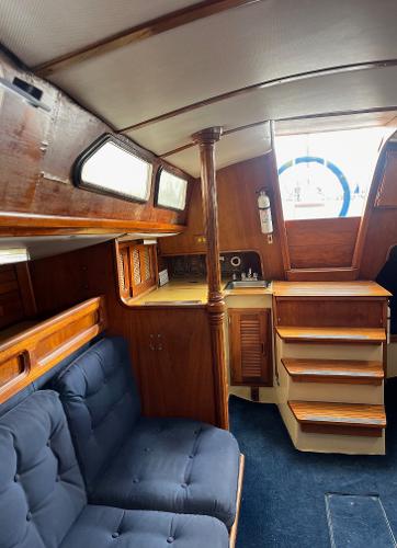 Interior of 1978 Islander Sloop 36 sailboat with wooden finishes and blue seating.