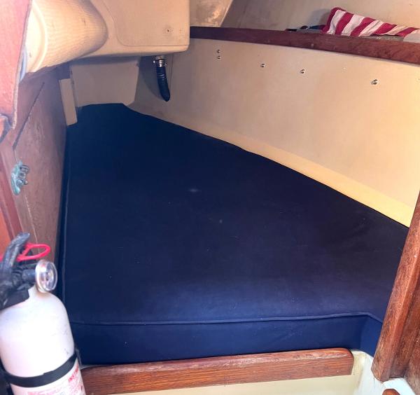 Interior cabin of 1978 Islander Sloop 36 sailboat with blue cushion and fire extinguisher.