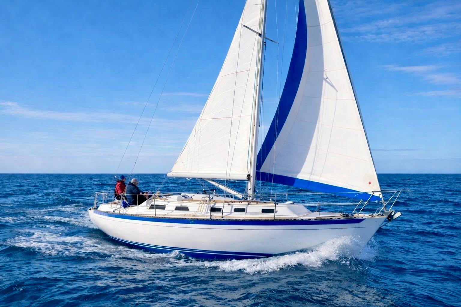 1978 Islander Sloop 36 sailing on open ocean under clear blue skies.