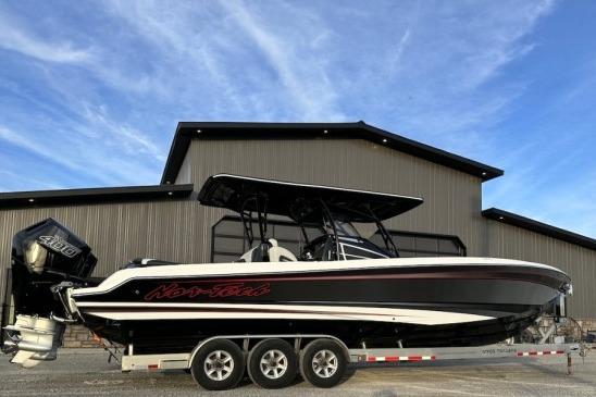 2024 Nor-Tech 340 Sport Center Console boat on trailer, against industrial building backdrop.