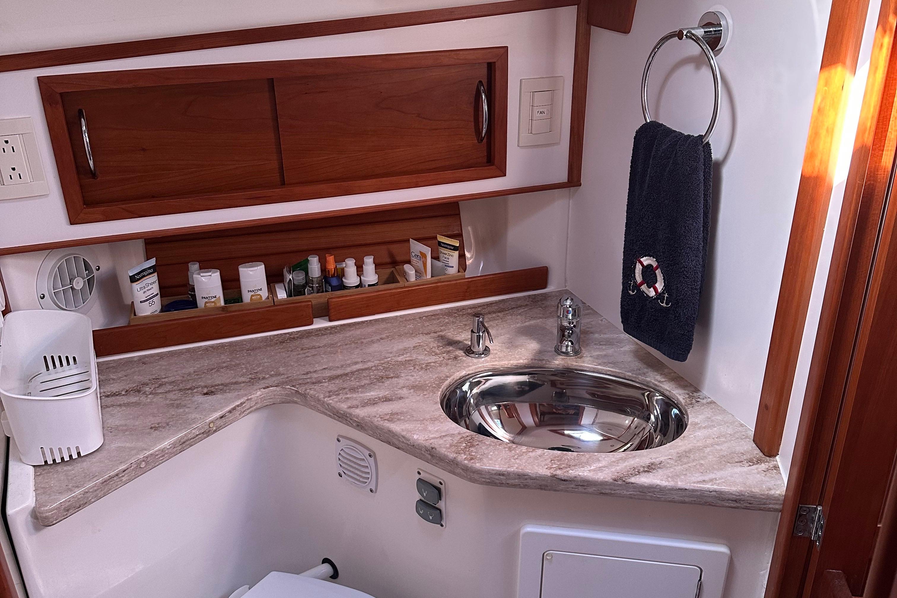 2017 Sabre 42 Salon Express bathroom with sink, wooden cabinets, and toiletries.