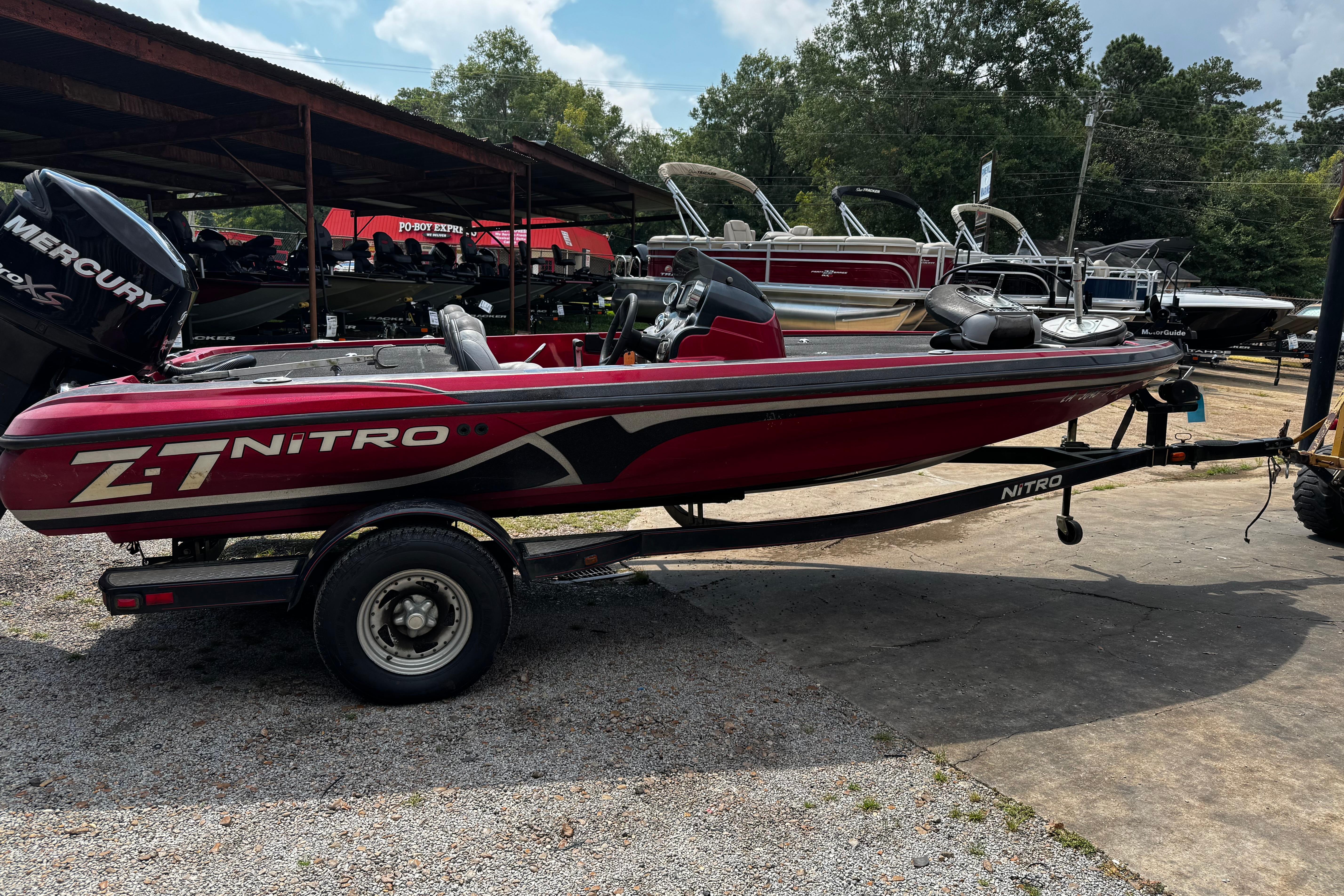Red 2011 Nitro Z7 boat on trailer, parked outdoors with other boats in background.