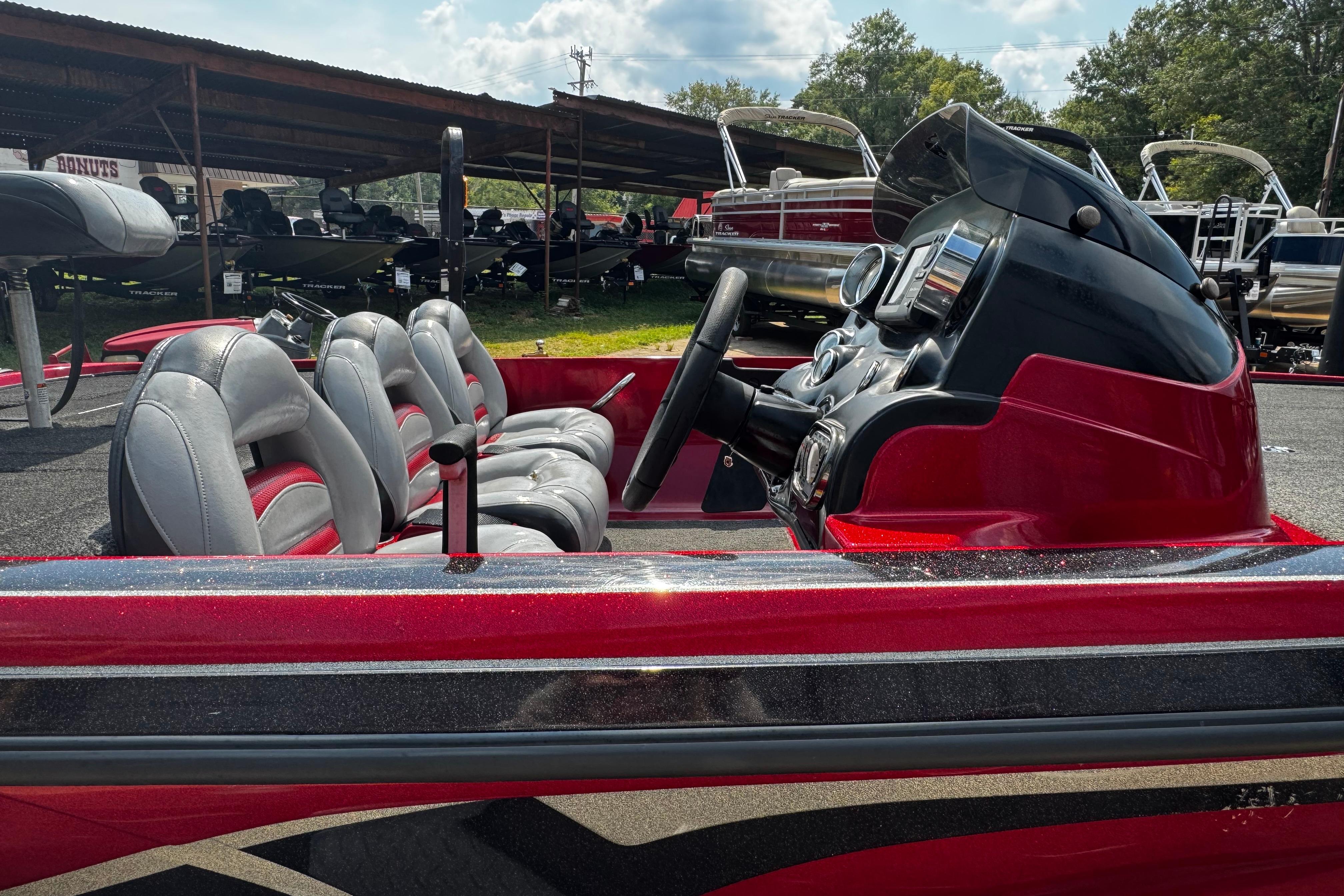 Red 2011 Nitro Z7 boat interior with steering wheel and seats, parked outdoors.