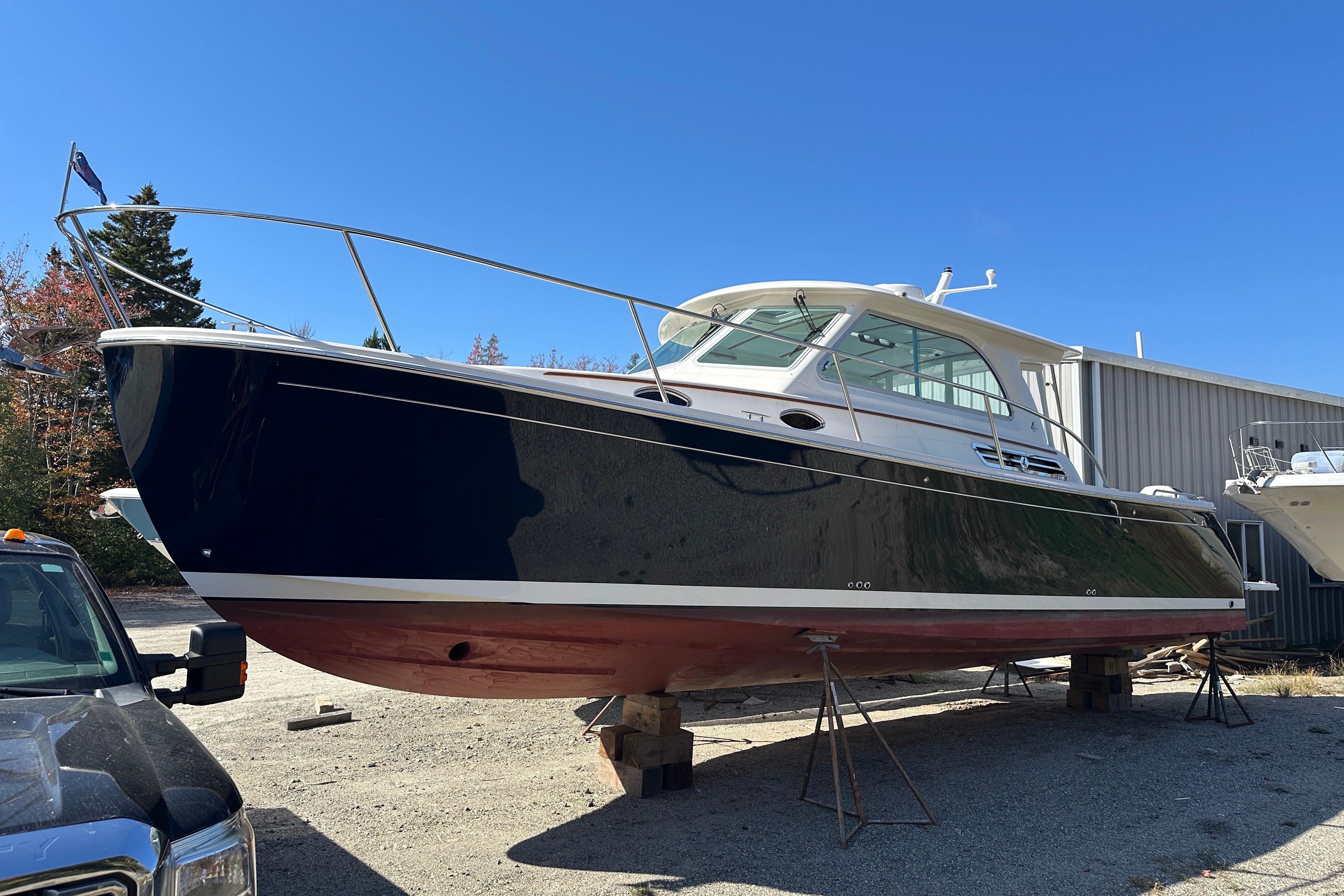 2024 Back Cove 34O boat on stands, outdoors, under clear blue sky.