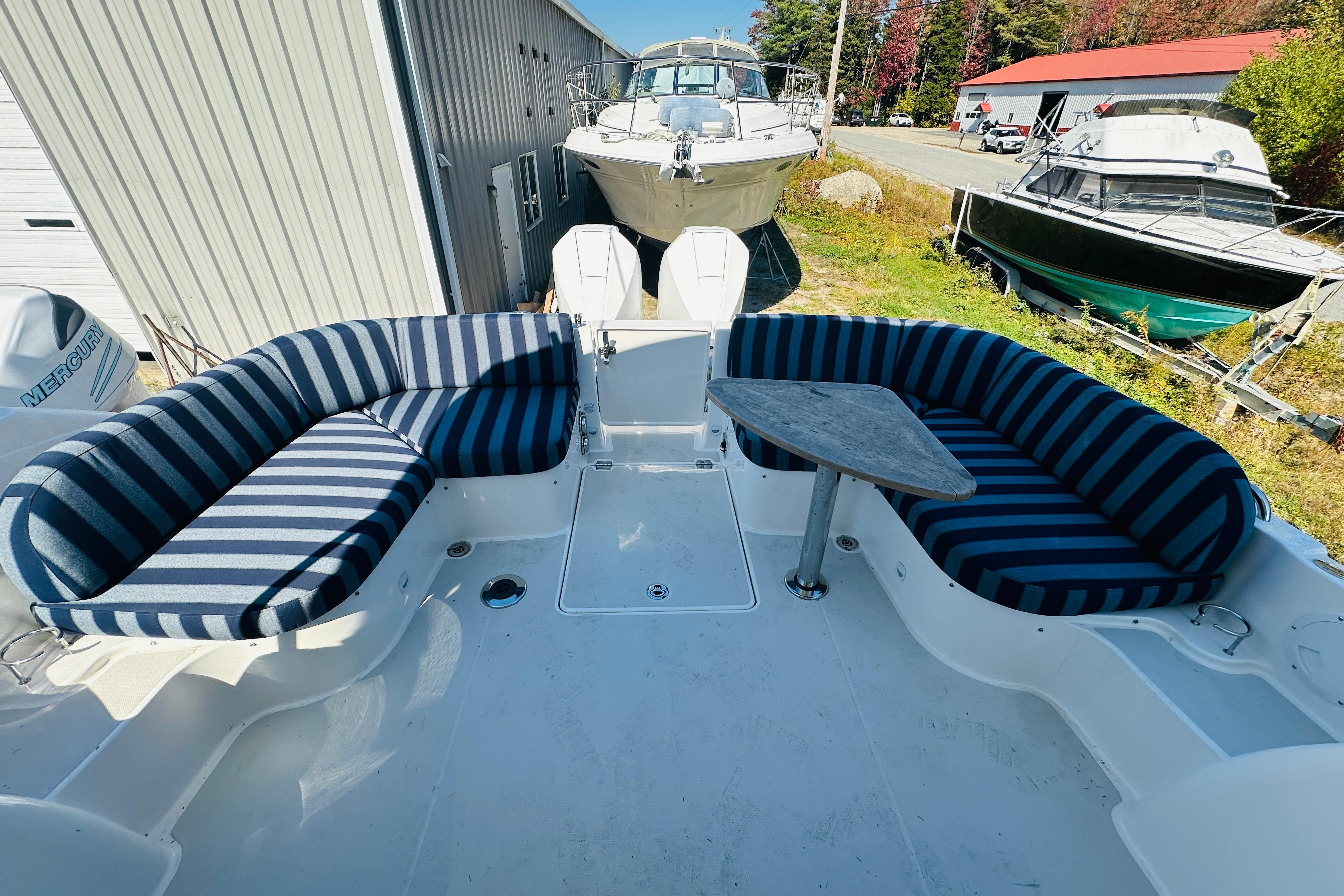 2024 Back Cove 34O boat with striped seating and table, docked near other boats.