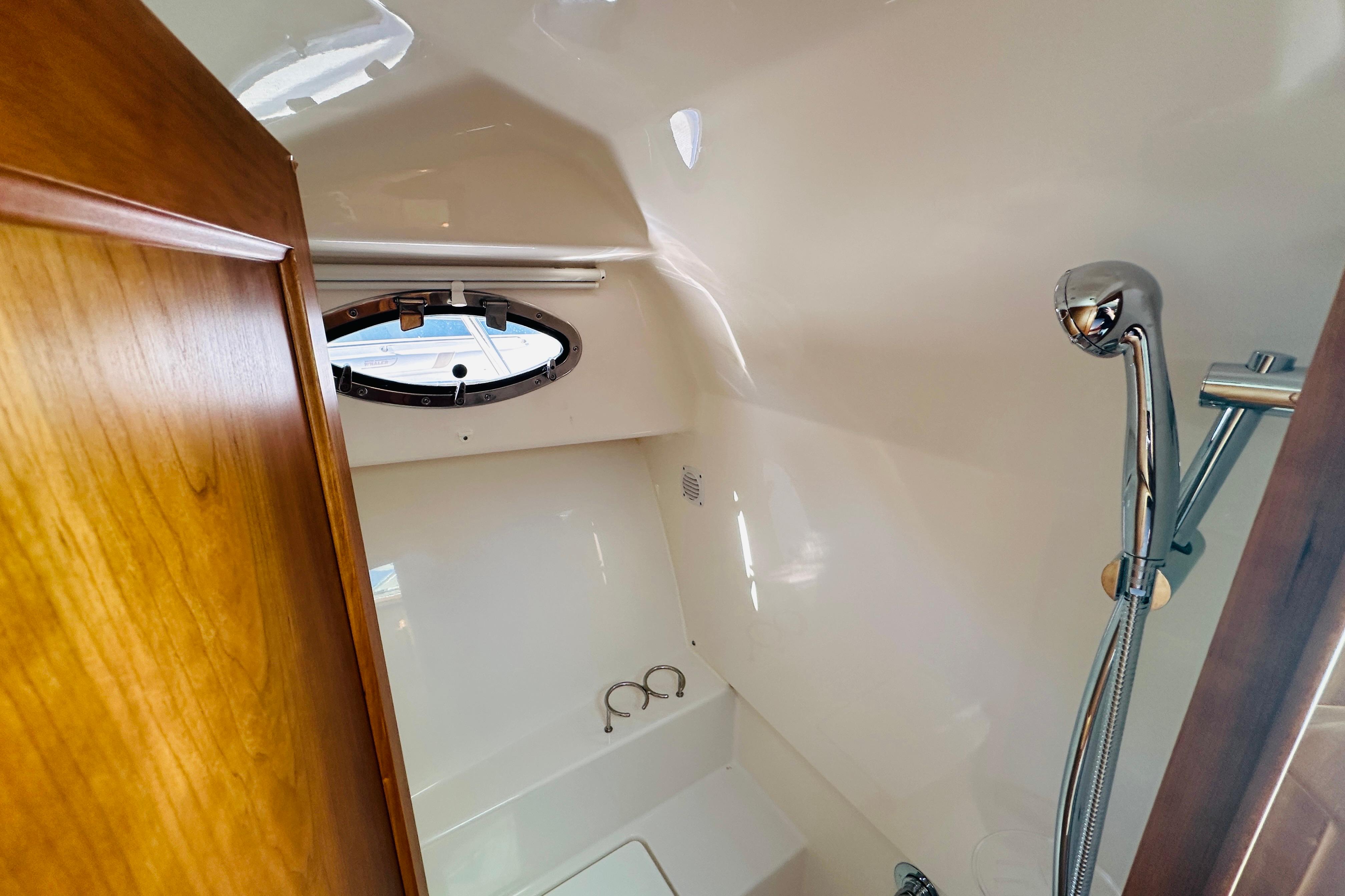 2024 Back Cove 34O yacht bathroom with showerhead and porthole window.