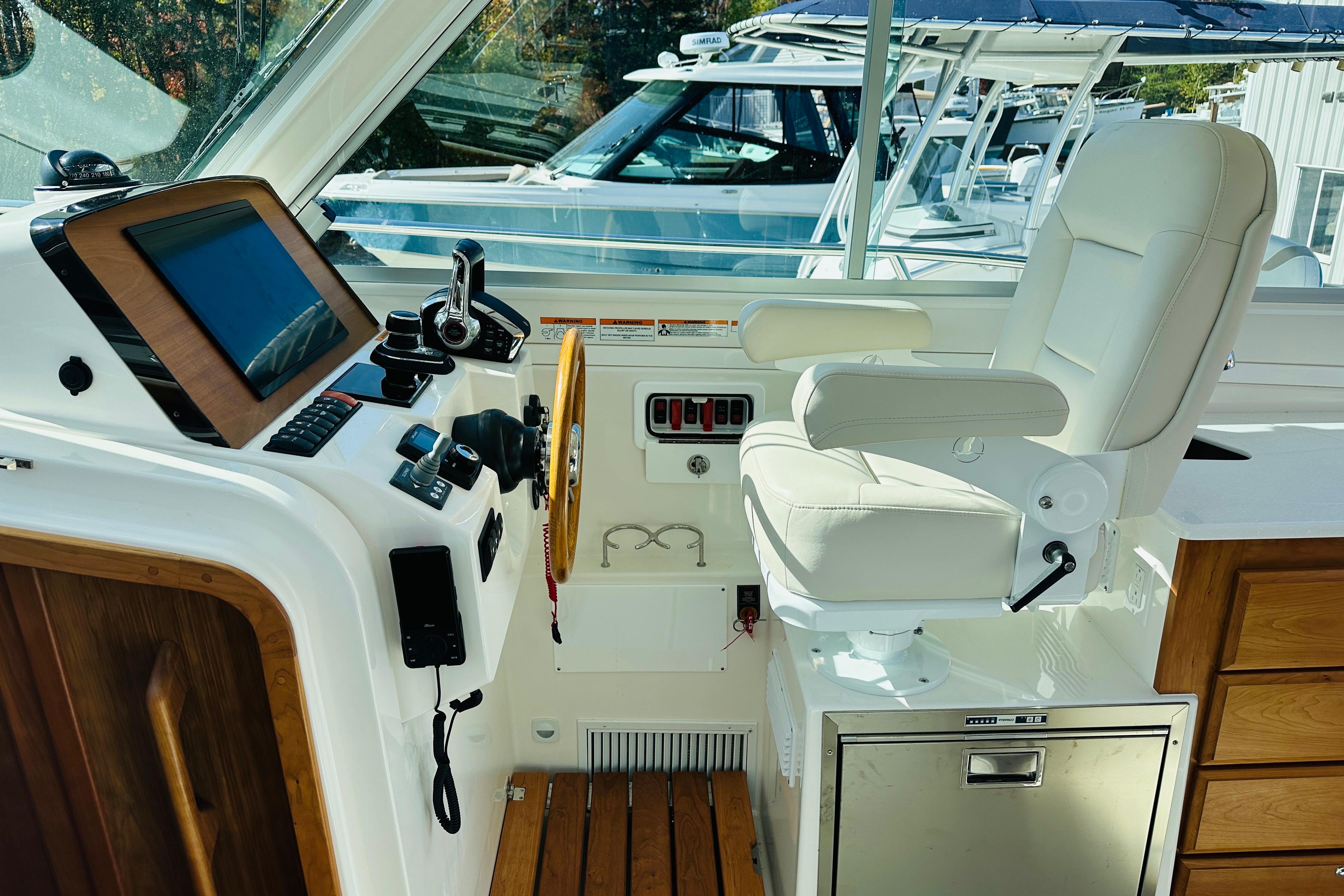 2024 Back Cove 34O helm with white captainu0027s chair and modern navigation controls.