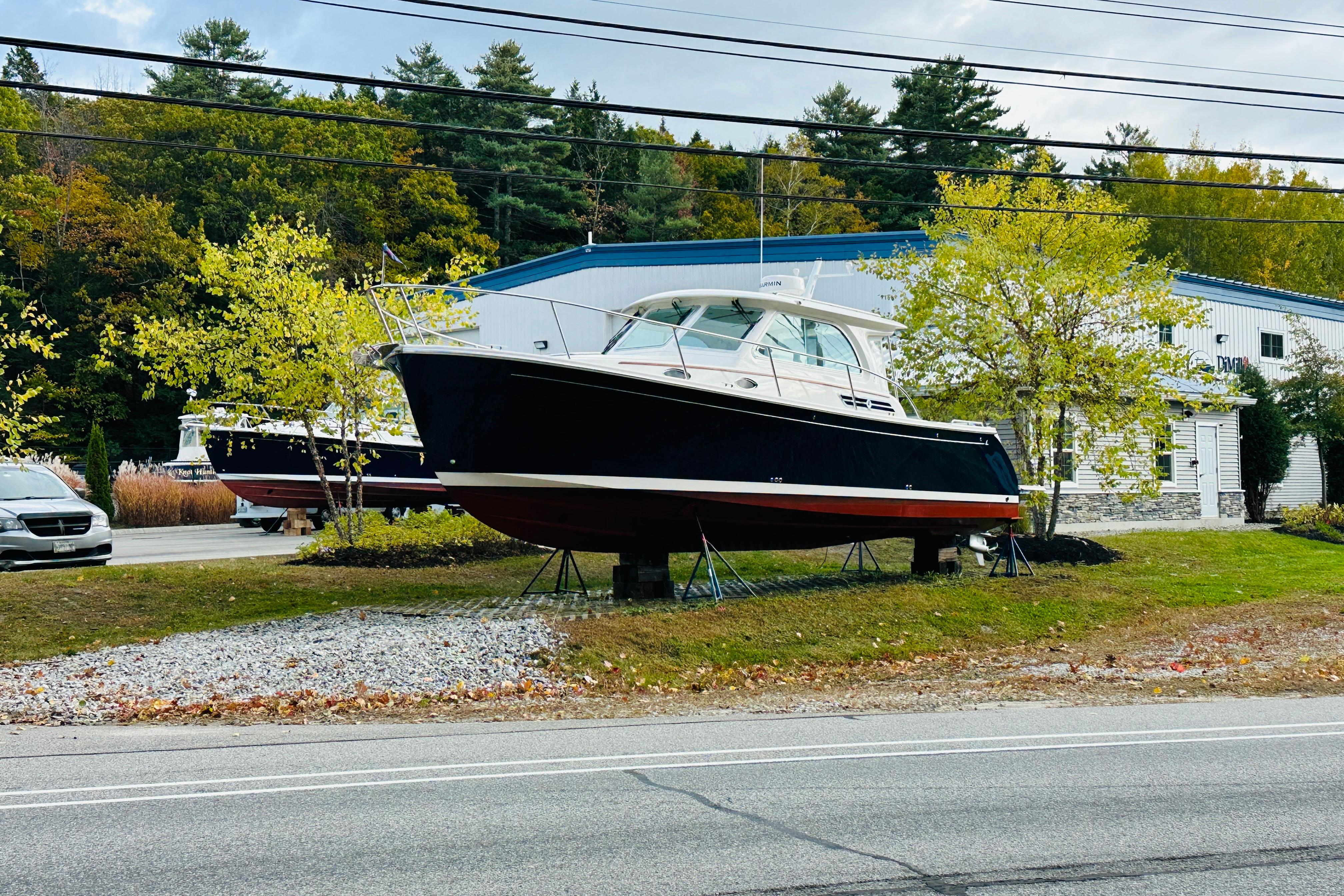 2024 Back Cove 34O boat displayed outdoors near a building, surrounded by trees.