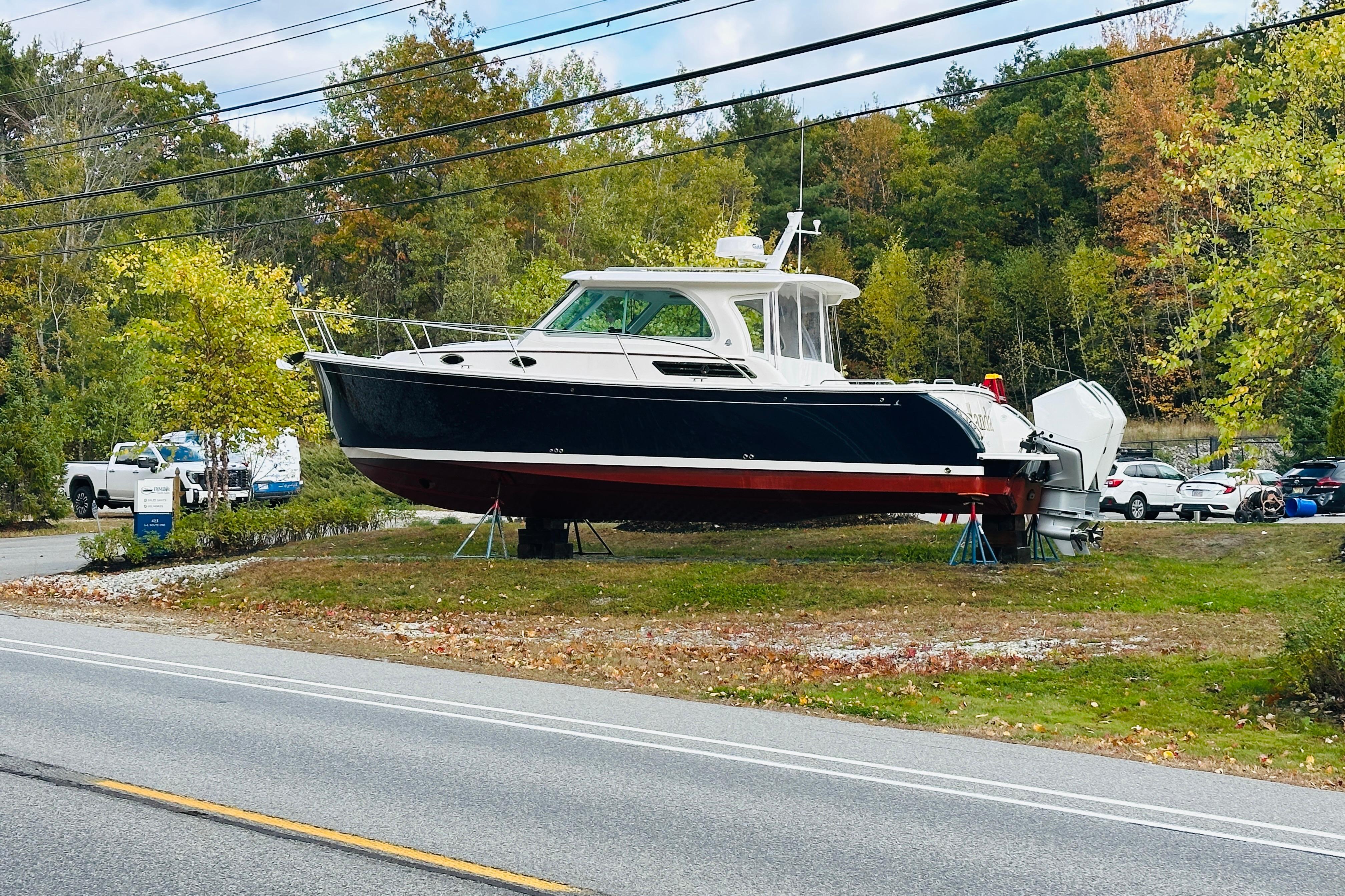 2024 Back Cove 34O boat on display, surrounded by autumn trees and parked cars.