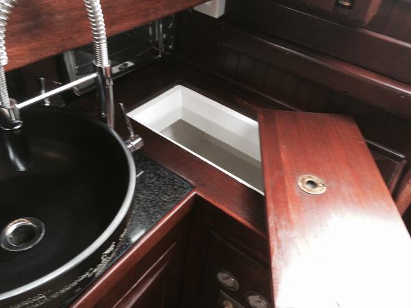 Interior of a 1971 Formosa 41 yacht with wooden cabinetry and a black sink.
