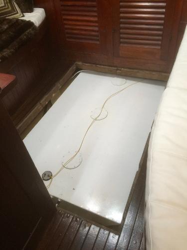 Interior view of a 1971 Formosa 41 sailboat, featuring a wooden floor and storage compartment.