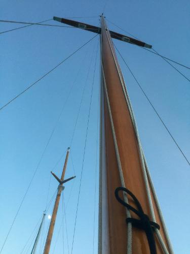 Tall wooden masts of a 1971 Formosa 41 sailboat against a clear blue sky.
