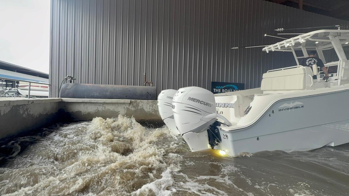 2022 Invincible 33 Catamaran with dual Mercury engines in turbulent water near a dock.