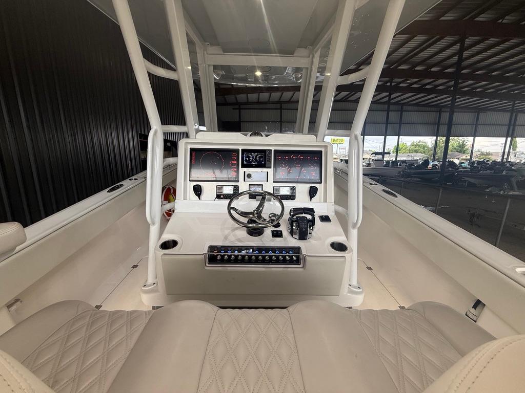 2022 Invincible 33 Catamaran cockpit with modern controls and steering wheel in a covered marina.