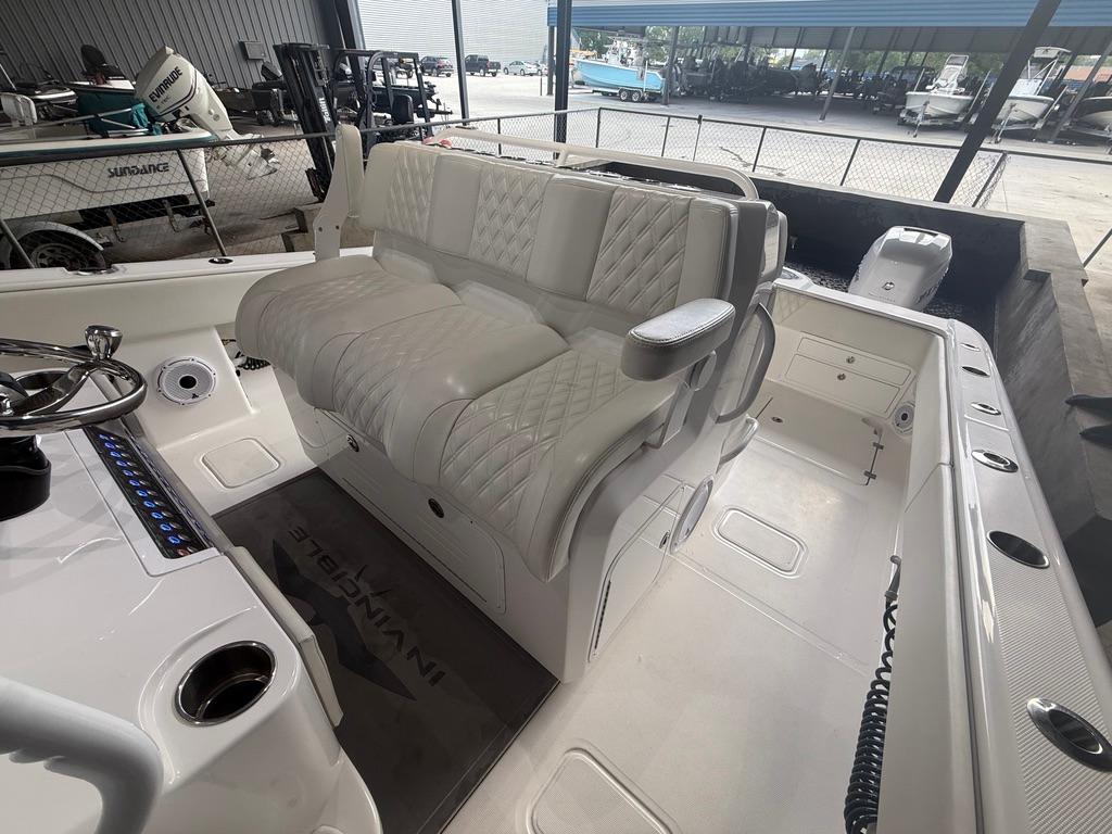 2022 Invincible 33 Catamaran interior with white seating and steering wheel in a showroom.
