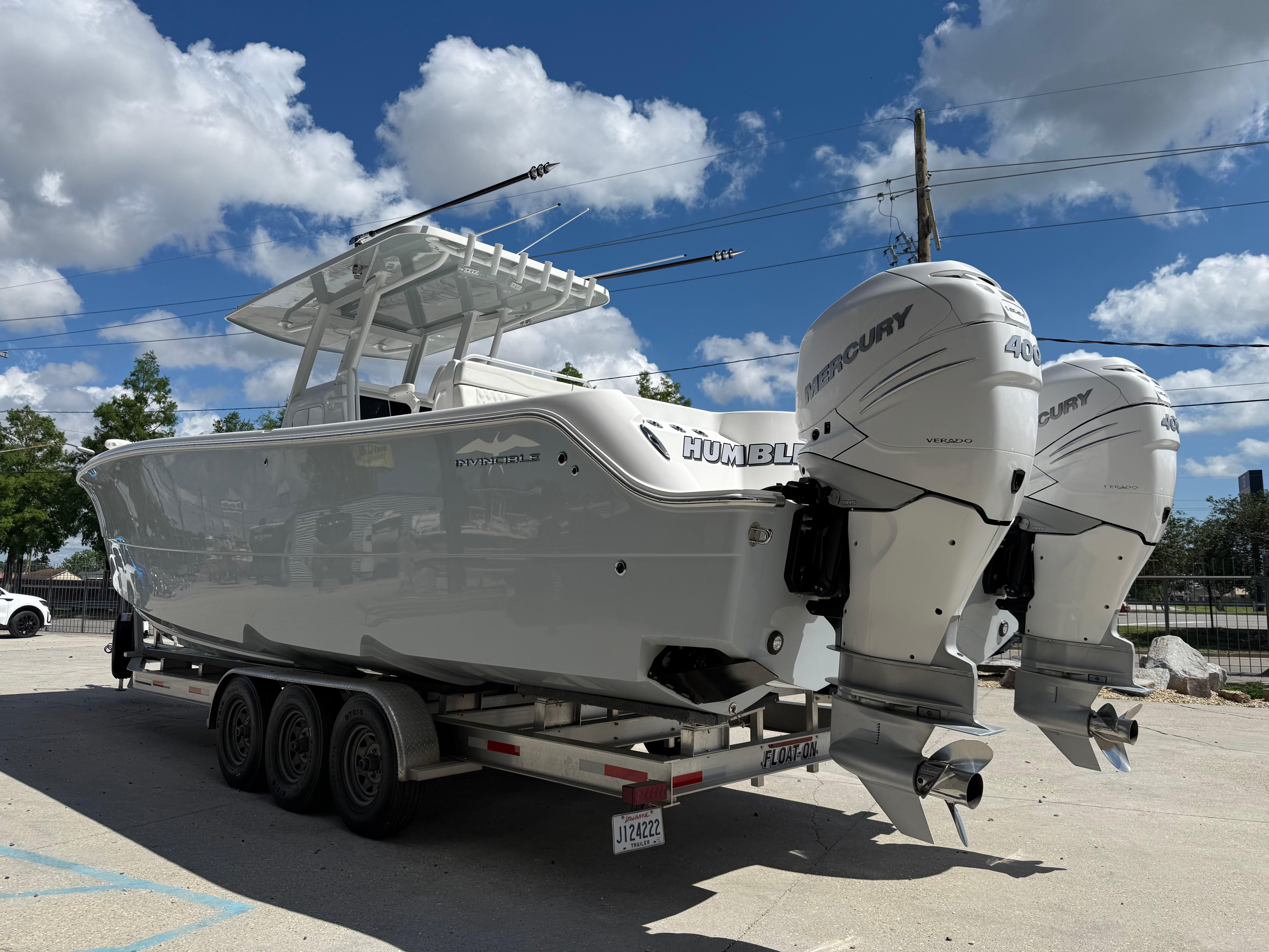2022 Invincible 33 Catamaran on trailer with twin Mercury outboard engines under a blue sky.