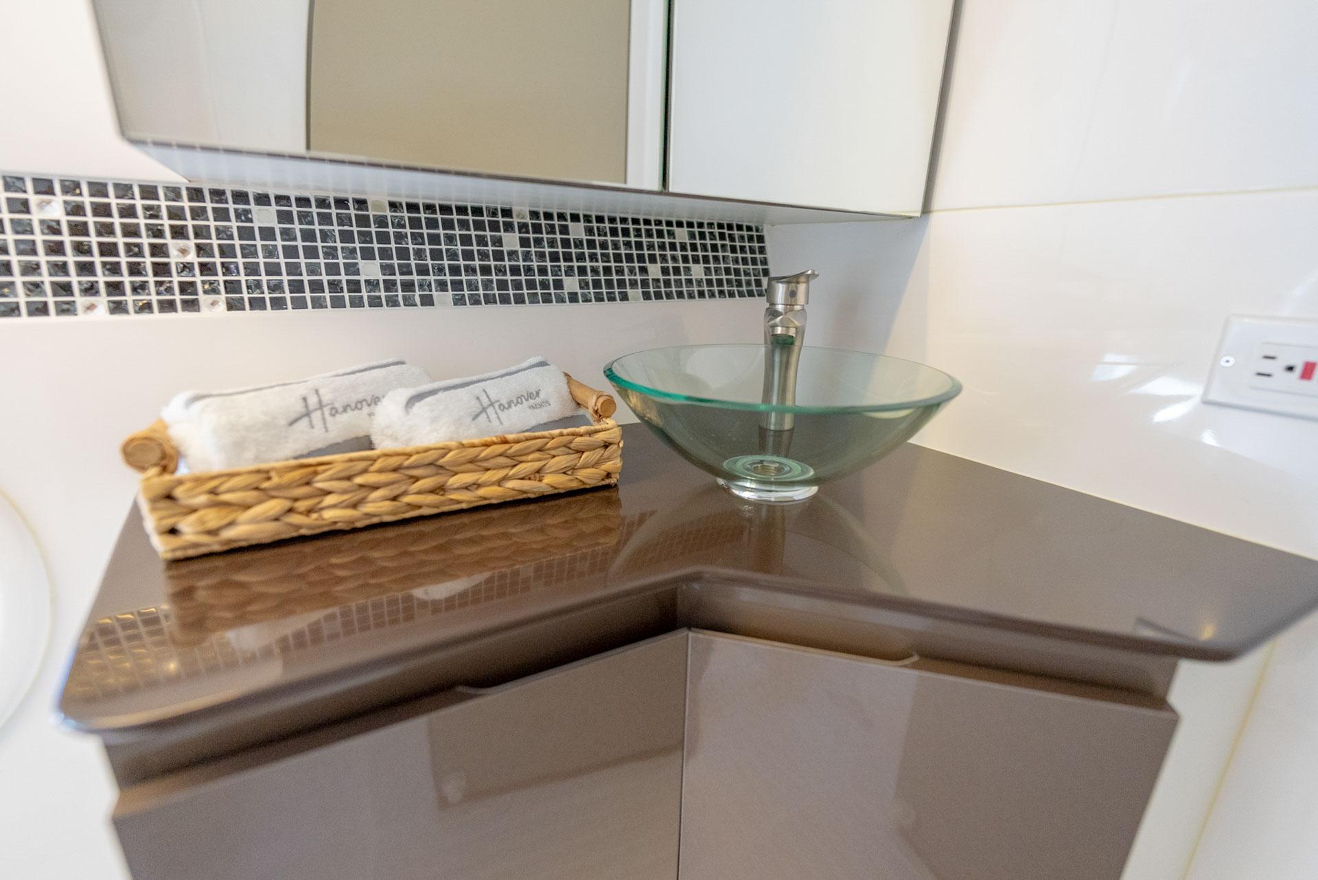 Hanover-415 2024-Music FL-US-Modern bathroom vanity with glass sink, mosaic backsplash, and wicker basket. Hanover 415, 2024 model.-9751409 | Thumbnail