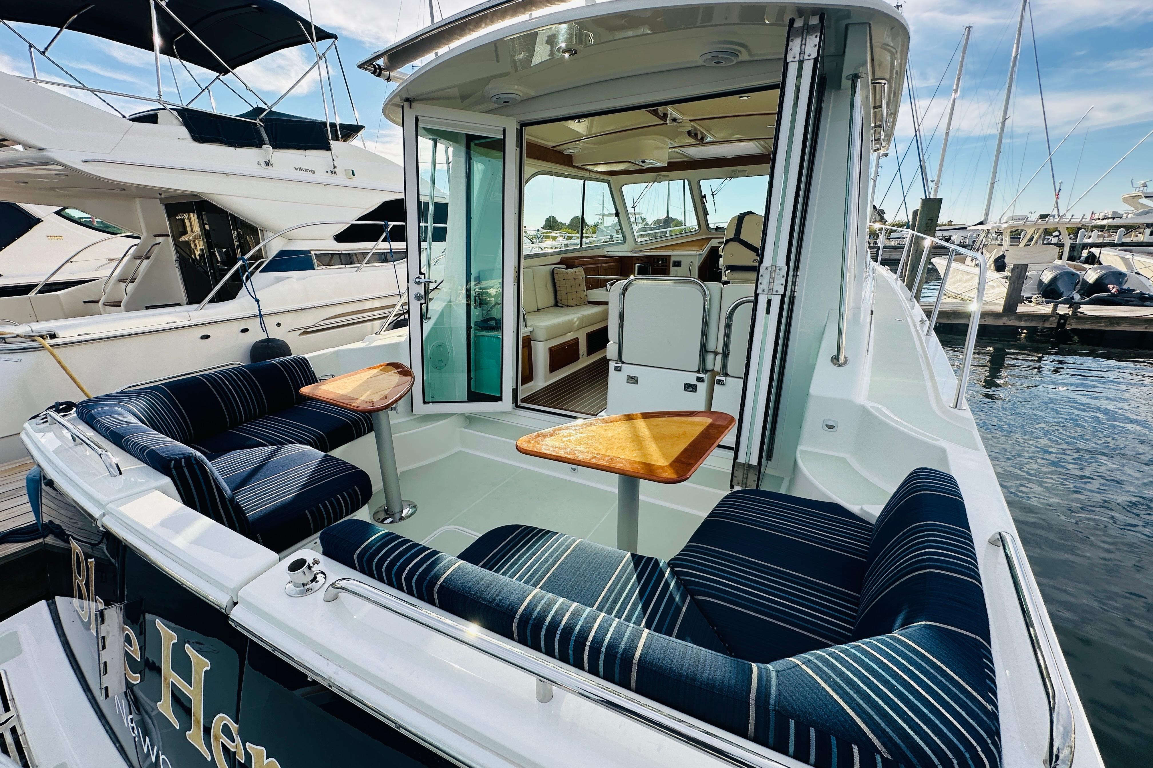 2020 Back Cove 37 yacht with striped seating and wooden tables at a marina.