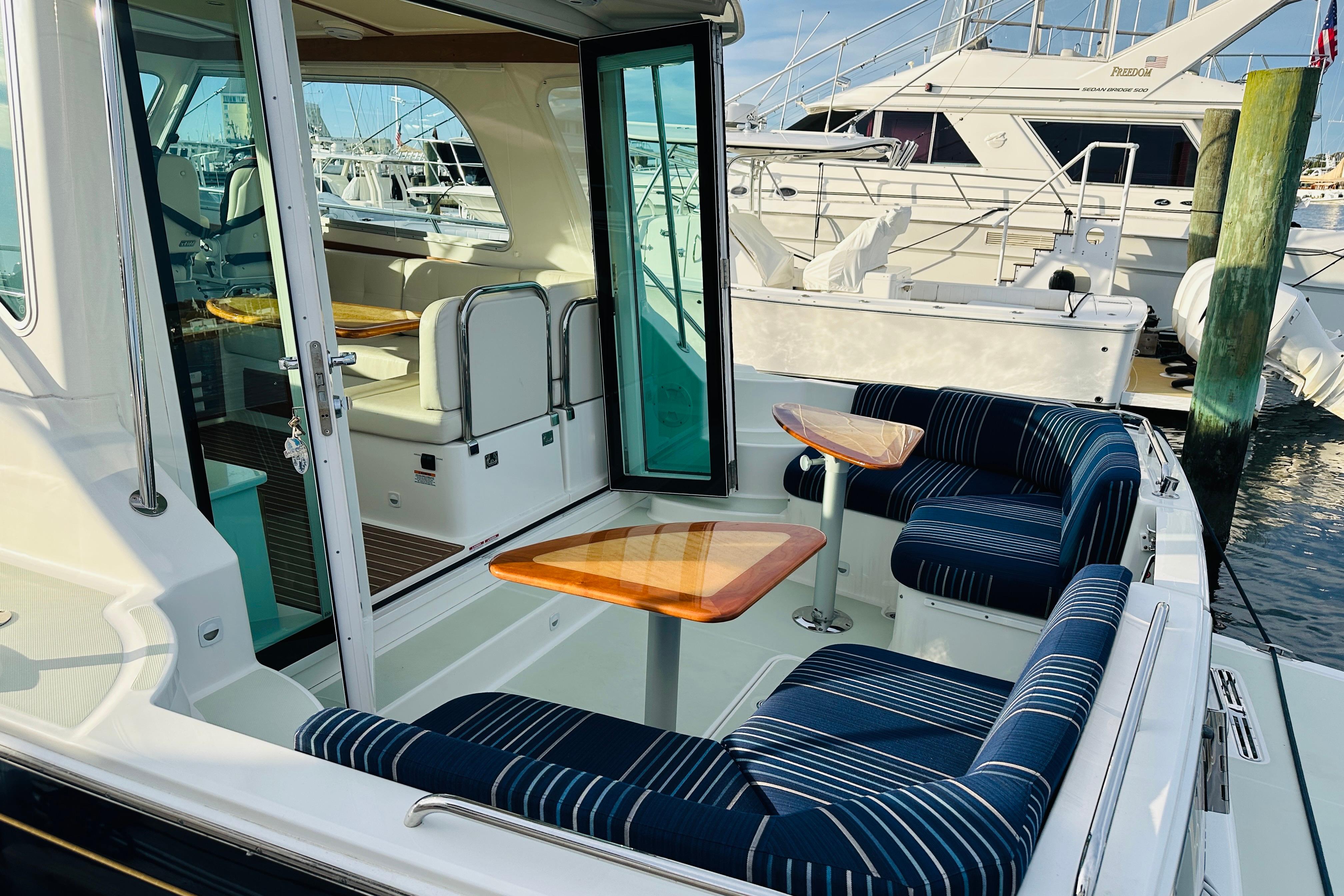 2020 Back Cove 37 yacht with elegant seating and wooden tables in a marina setting.