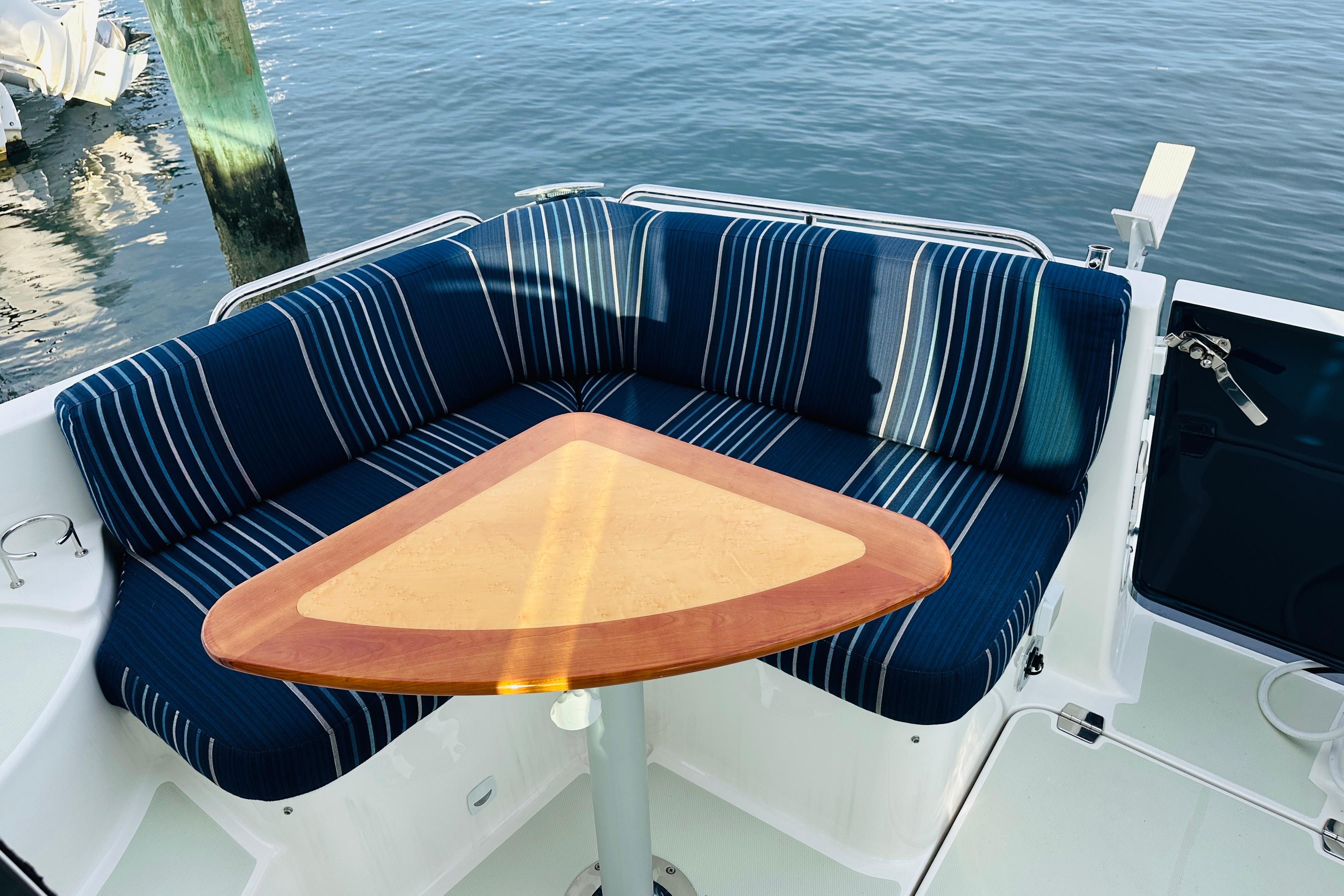 Cozy seating area on 2020 Back Cove 37 yacht with striped cushions and triangular table.