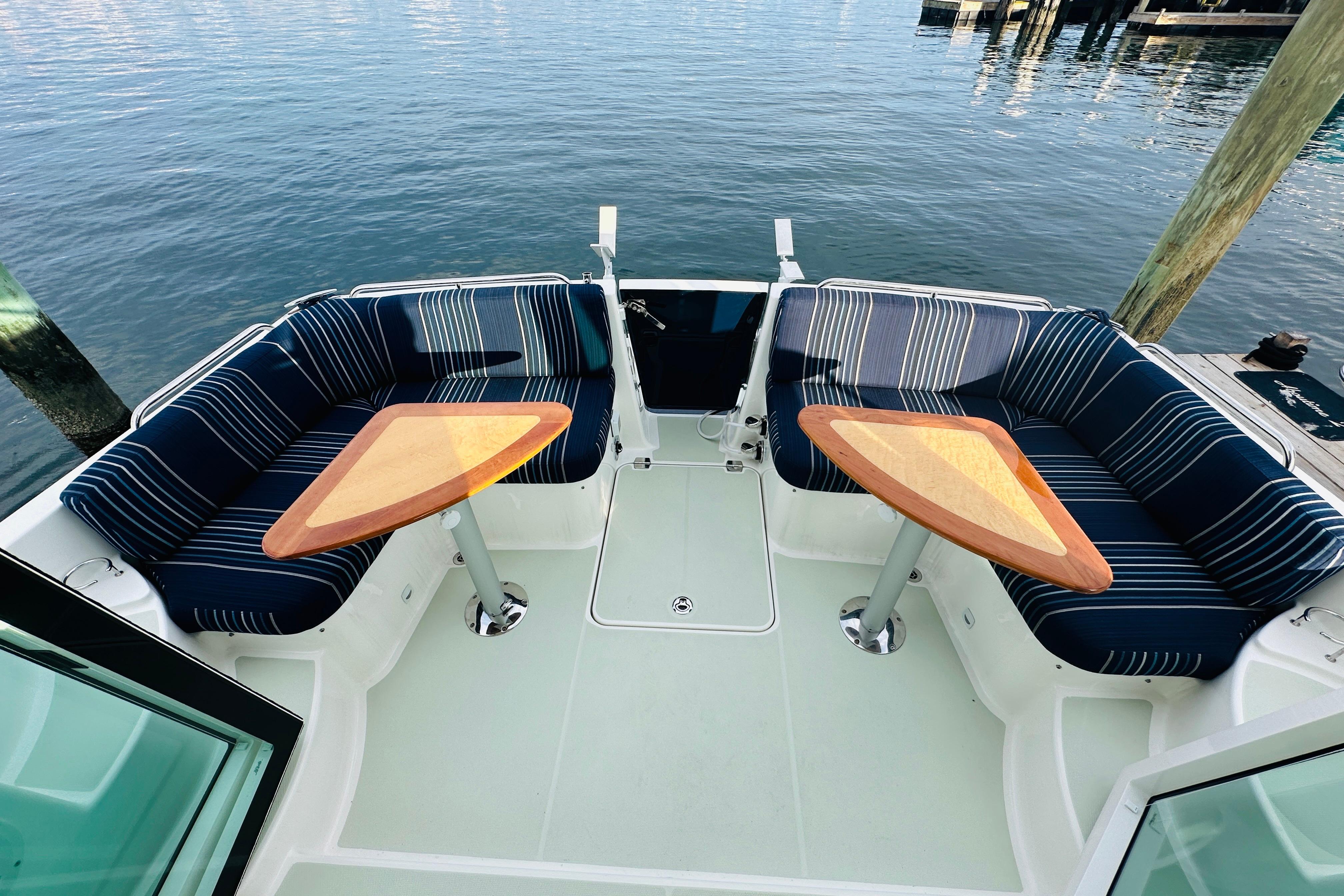 2020 Back Cove 37 boat with striped seating and wooden tables on deck.