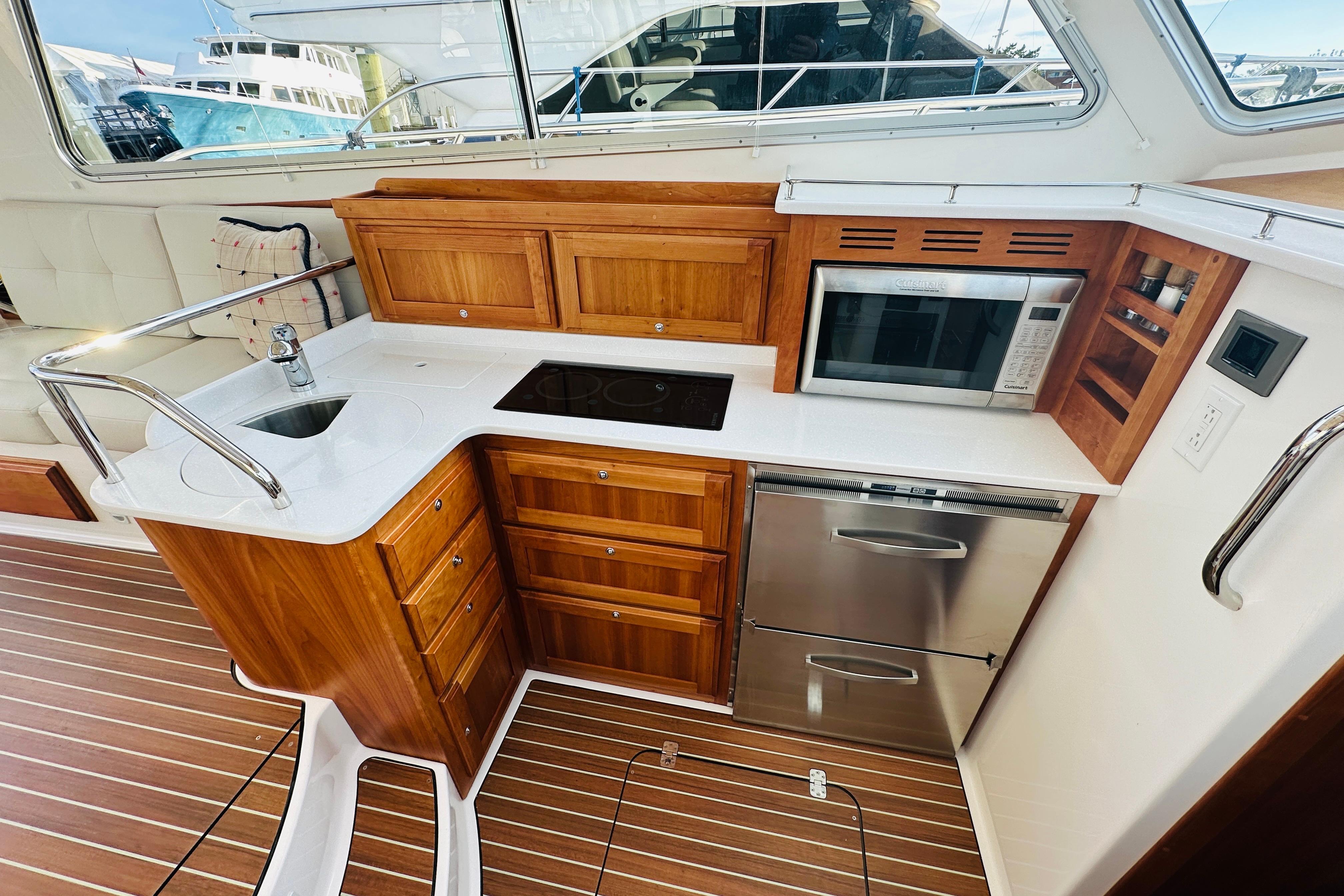 Modern galley kitchen in 2020 Back Cove 37 yacht with wood cabinetry and stainless steel appliances.