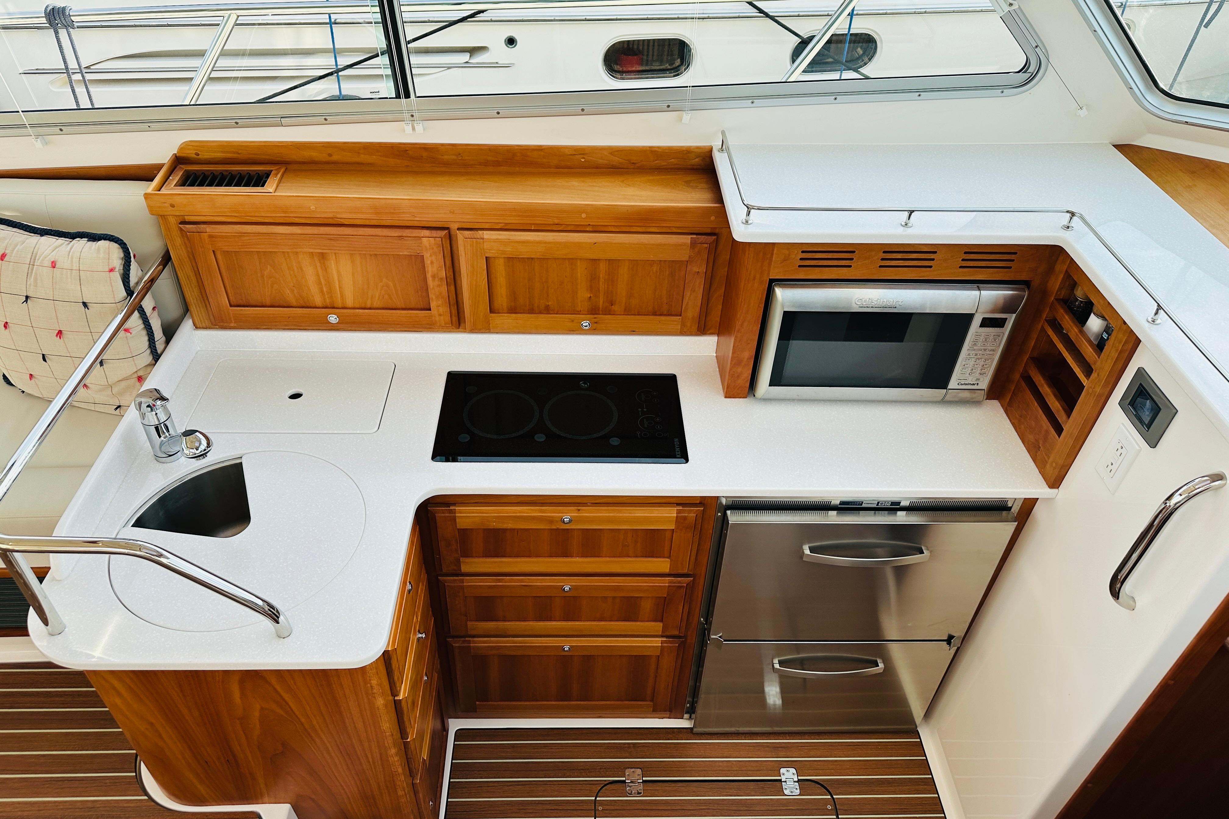 Modern galley kitchen in 2020 Back Cove 37 yacht with wood cabinetry and stainless steel appliances.