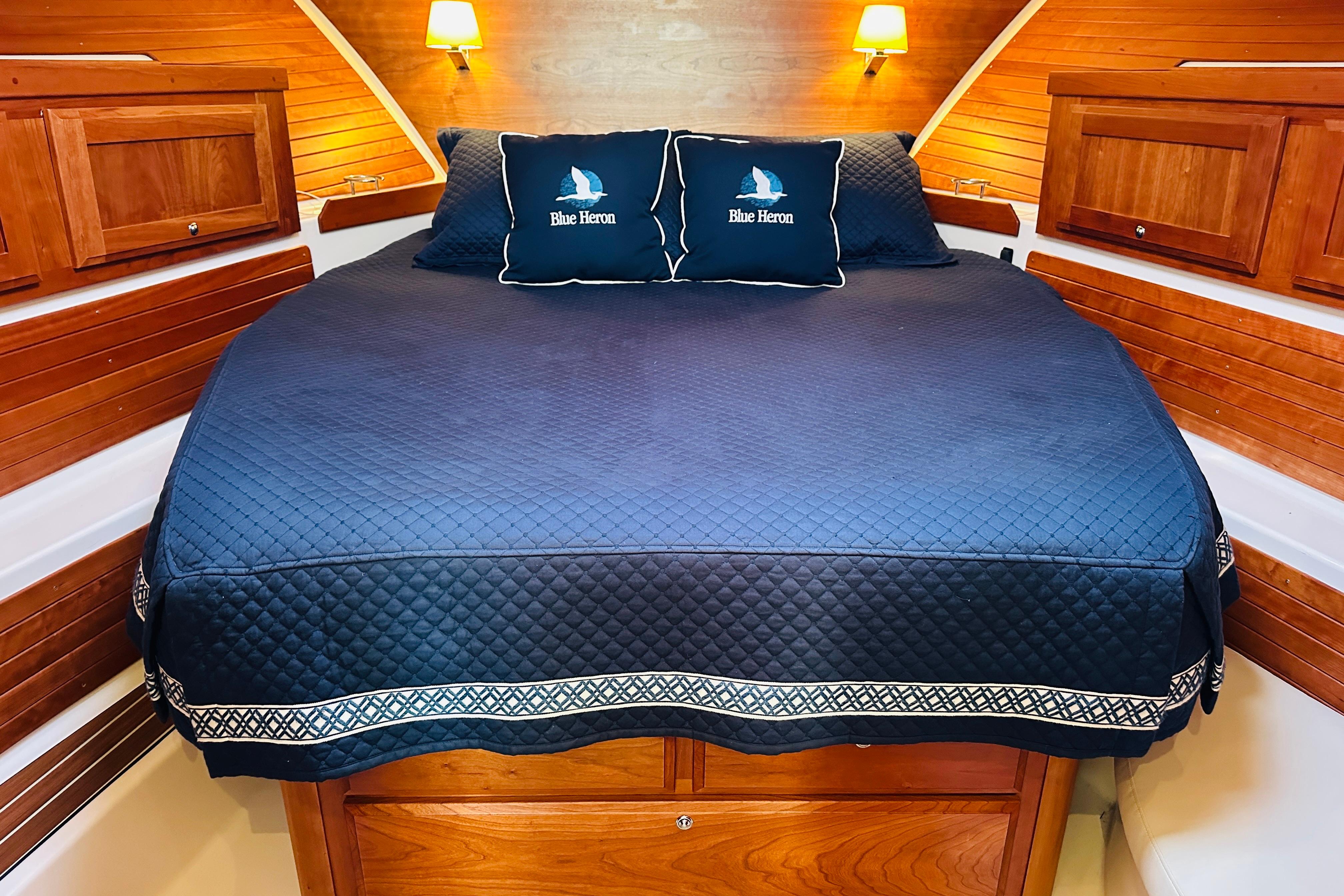 Cozy cabin interior of 2020 Back Cove 37 with elegant wood paneling and navy bedding.