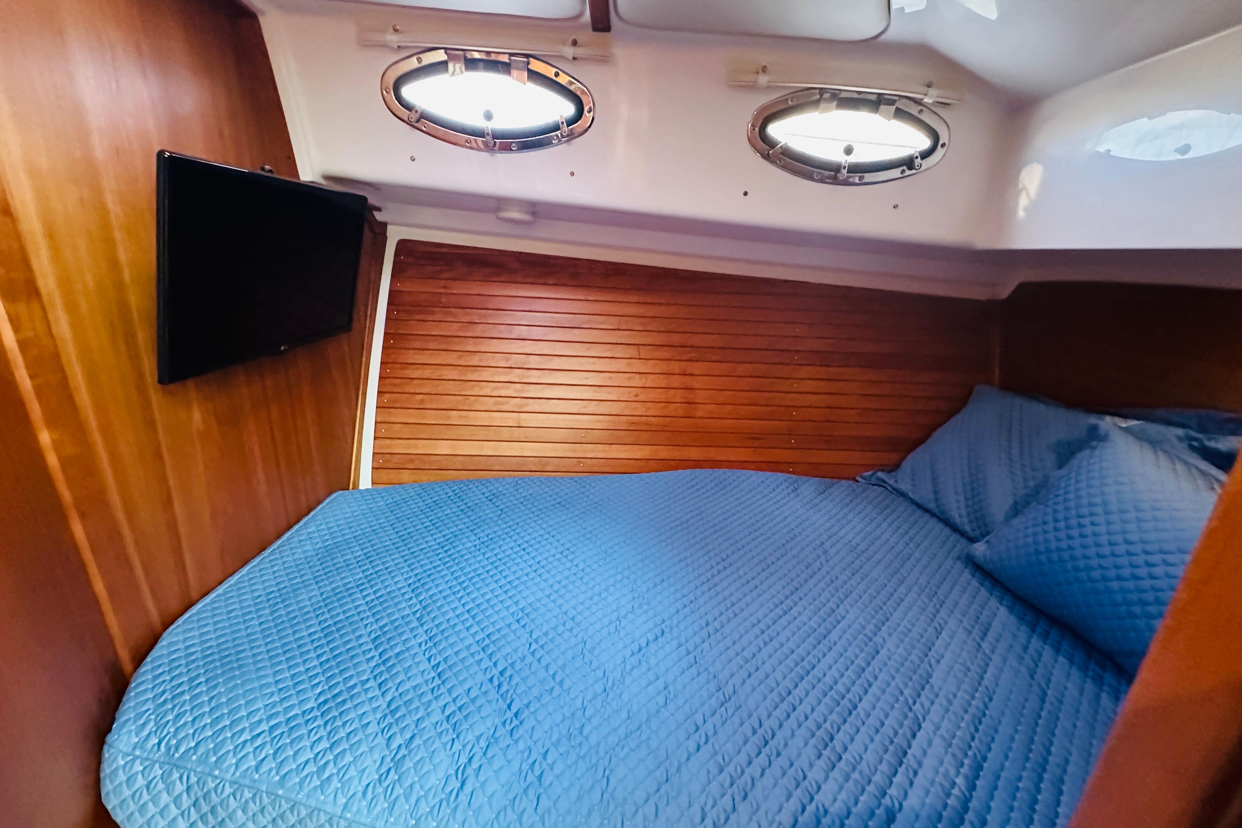 Cozy cabin interior of 2020 Back Cove 37 with blue bedding and portholes.