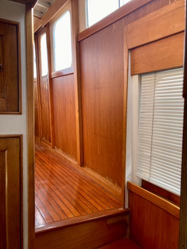 Interior of 1977 Grand Alaskan Raised Pilothouse with polished wood paneling and windows.