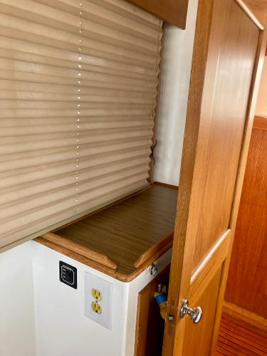 Interior of 1977 Grand Alaskan Raised Pilothouse with wooden cabinetry and blinds.