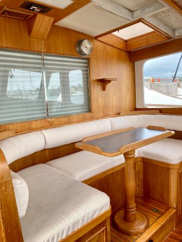1977 Grand Alaskan Raised Pilothouse interior with wooden dining area and cushioned seating.