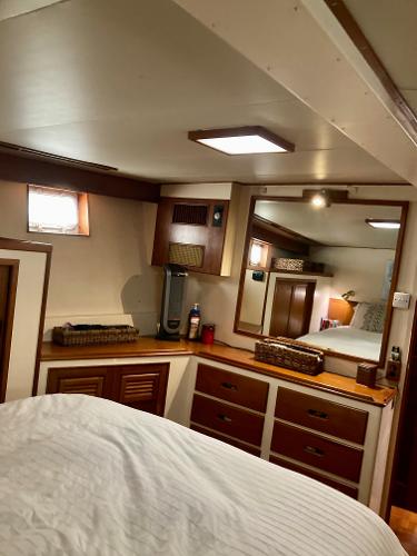 Cozy cabin interior of 1977 Grand Alaskan Raised Pilothouse with wooden furnishings and mirror.