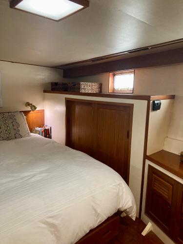 Cozy bedroom in 1977 Grand Alaskan Raised Pilothouse with wood accents and natural light.