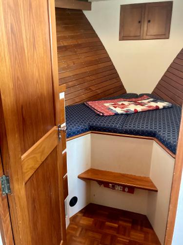 Cozy cabin interior of 1977 Grand Alaskan Raised Pilothouse with wooden accents and quilted bedding.