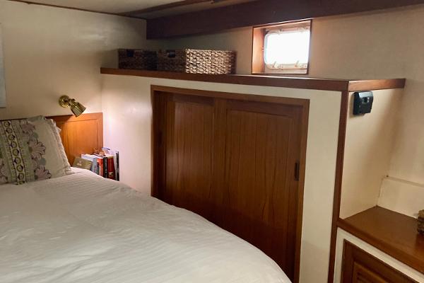 Cozy bedroom in 1977 Grand Alaskan Raised Pilothouse with wooden accents and natural light.