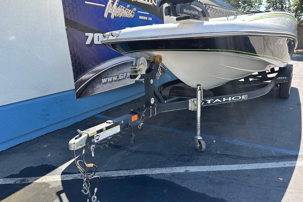 2019 Tahoe 2150 boat on trailer, parked outdoors, with visible hitch and signage in background.