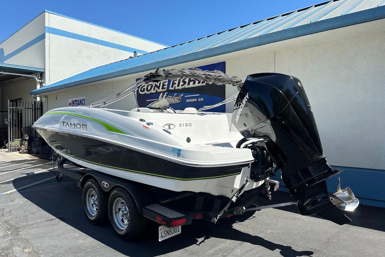 2019 Tahoe 2150 boat with Mercury engine on trailer, parked outside a building.