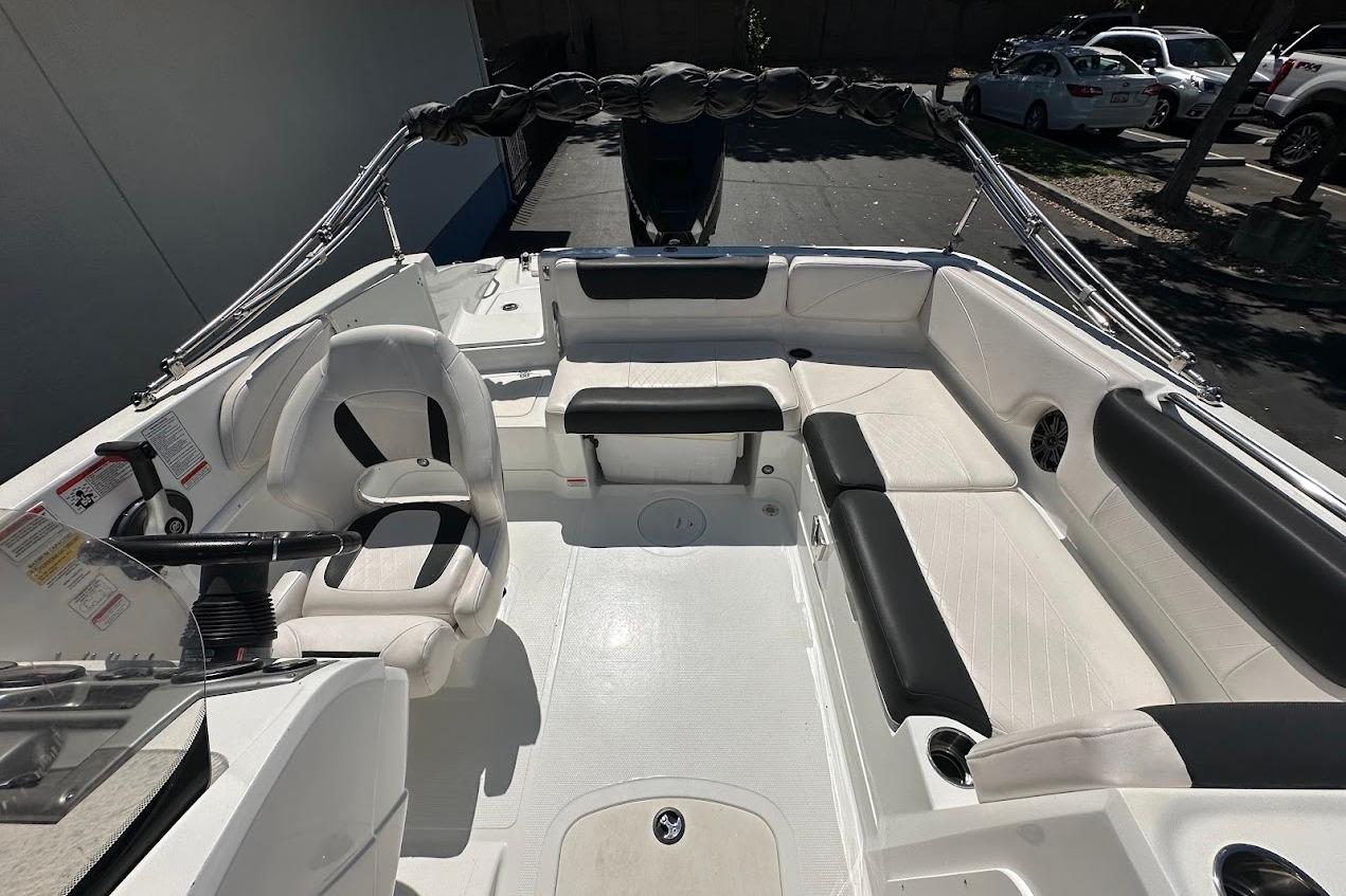 2019 Tahoe 2150 boat interior with white and black seating, steering wheel, and cup holders.