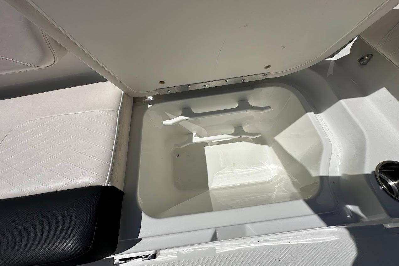 Open storage compartment in 2019 Tahoe 2150 boat, featuring white interior and seating.