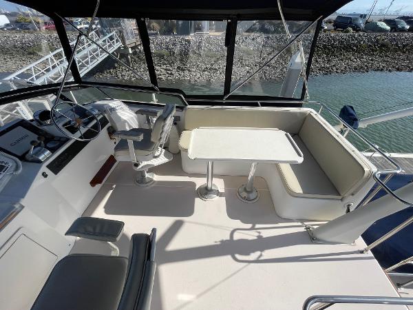 1997 Sabre Cockpit Motor Yacht interior with helm, seating, and table, docked by the water.