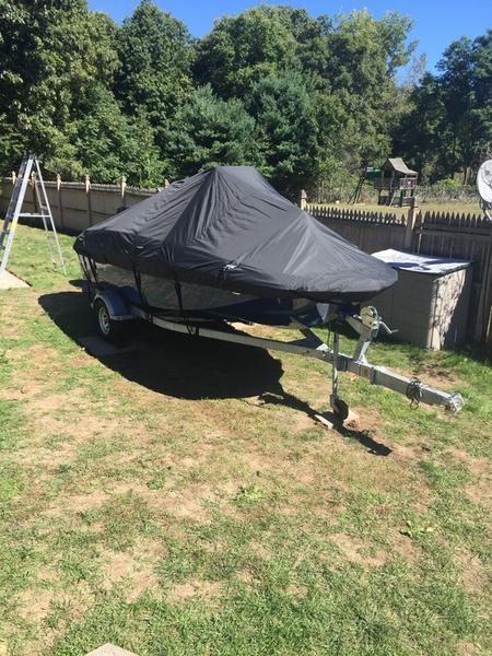 2017 Bayliner Element F18 CC boat covered, parked on grass with trees in the background.