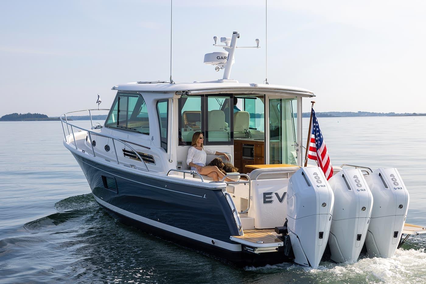 2027 Back Cove 39O boat cruising with American flag and triple outboard engines.