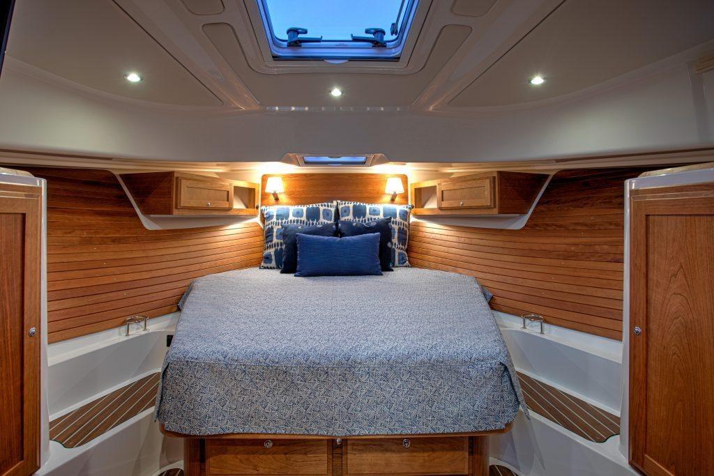 Luxurious cabin interior of 2027 Back Cove 39O yacht with cozy bed and wooden accents.