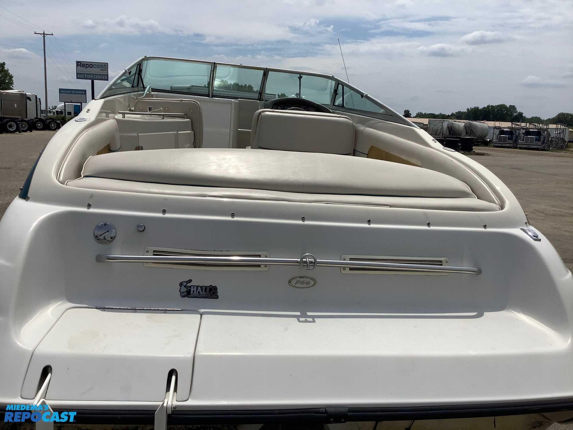 1999 Crownline 266 CCR boat, rear view, white seating, parked outdoors.