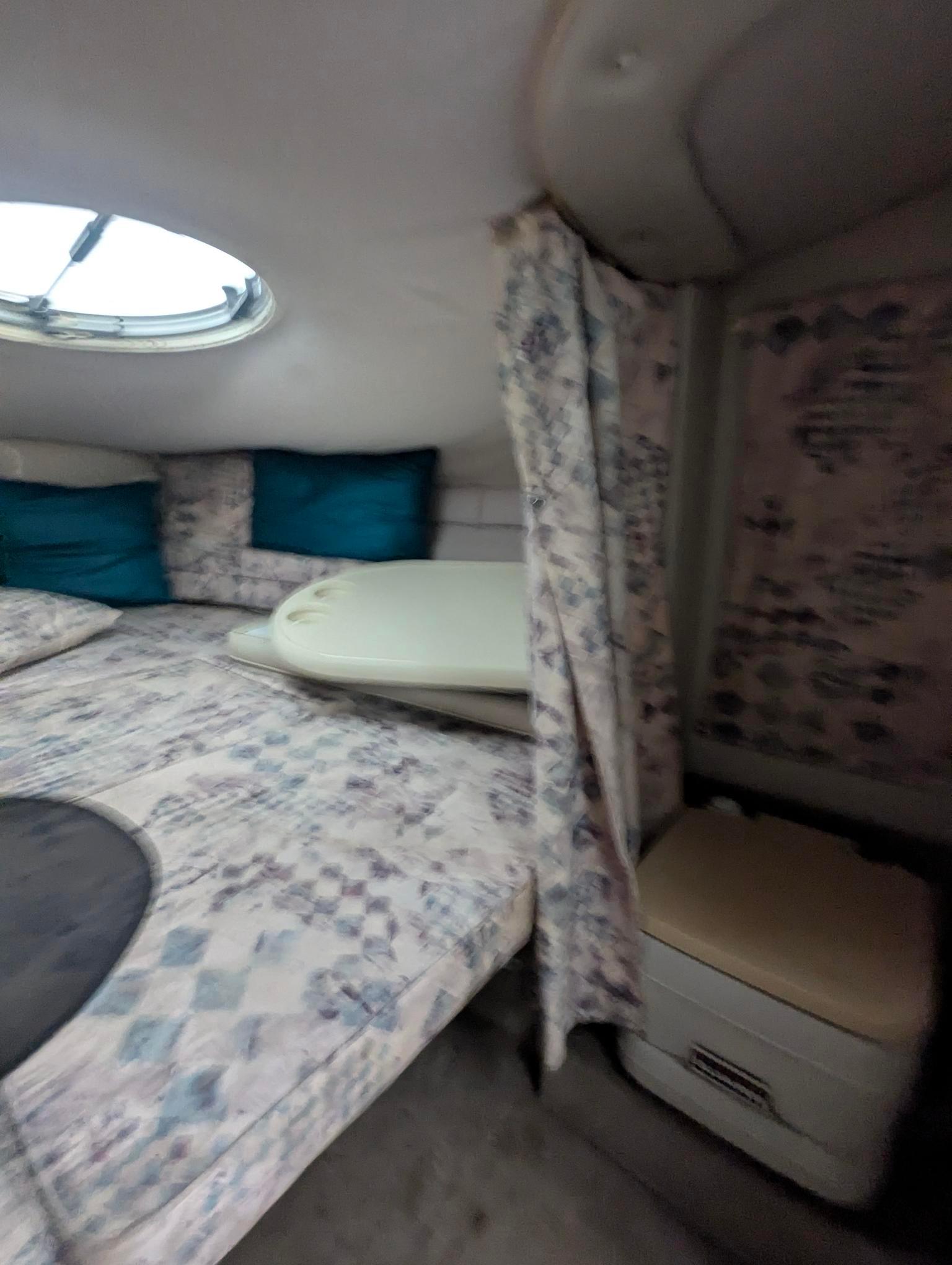 1999 Crownline 266 CCR cabin interior with patterned bedding and small window.